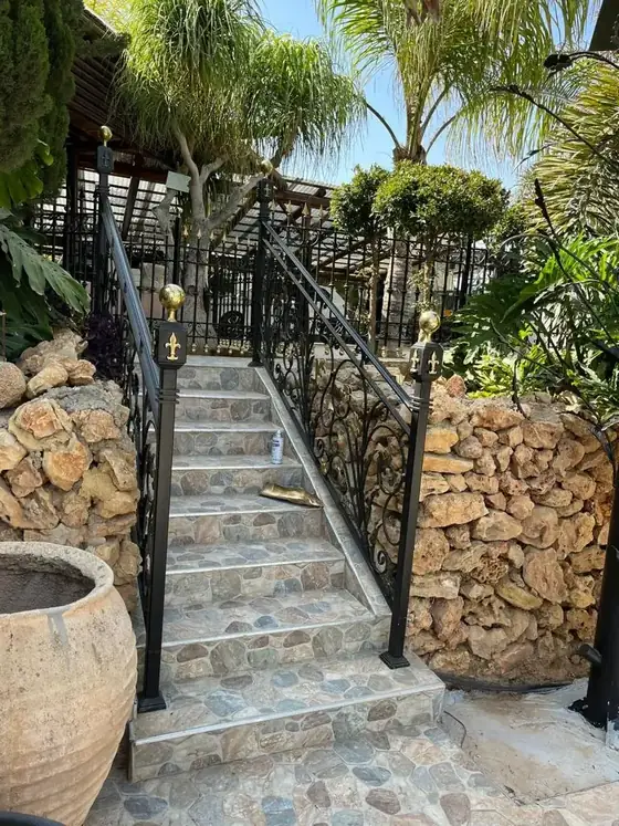 מעקה ברזל לאורך מדרגות אבן בגינה