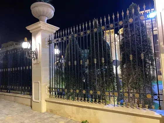 גדר ברזל מעוטרת בתאורת לילה בכניסה לאחוזה