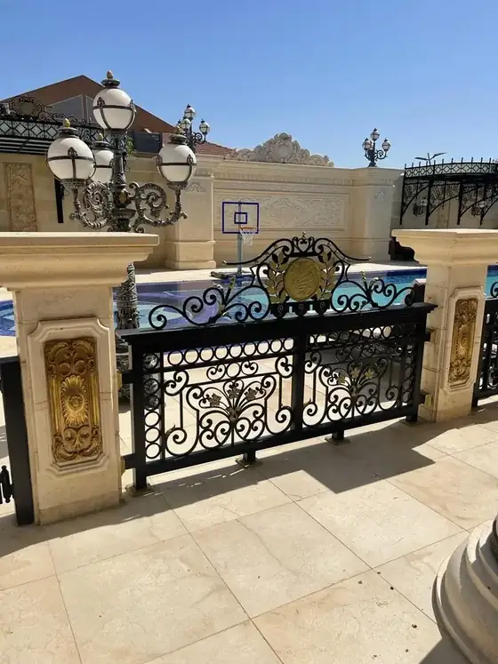 מעקה חוץ מעוטר ביציקות פליז מוזהבות סביב בריכת האחוזה
