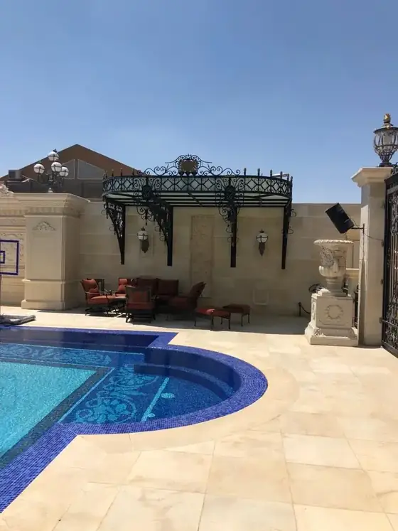 פרגולת ברזל מעוטרת מעל פינת הישיבה שליד הבריכה